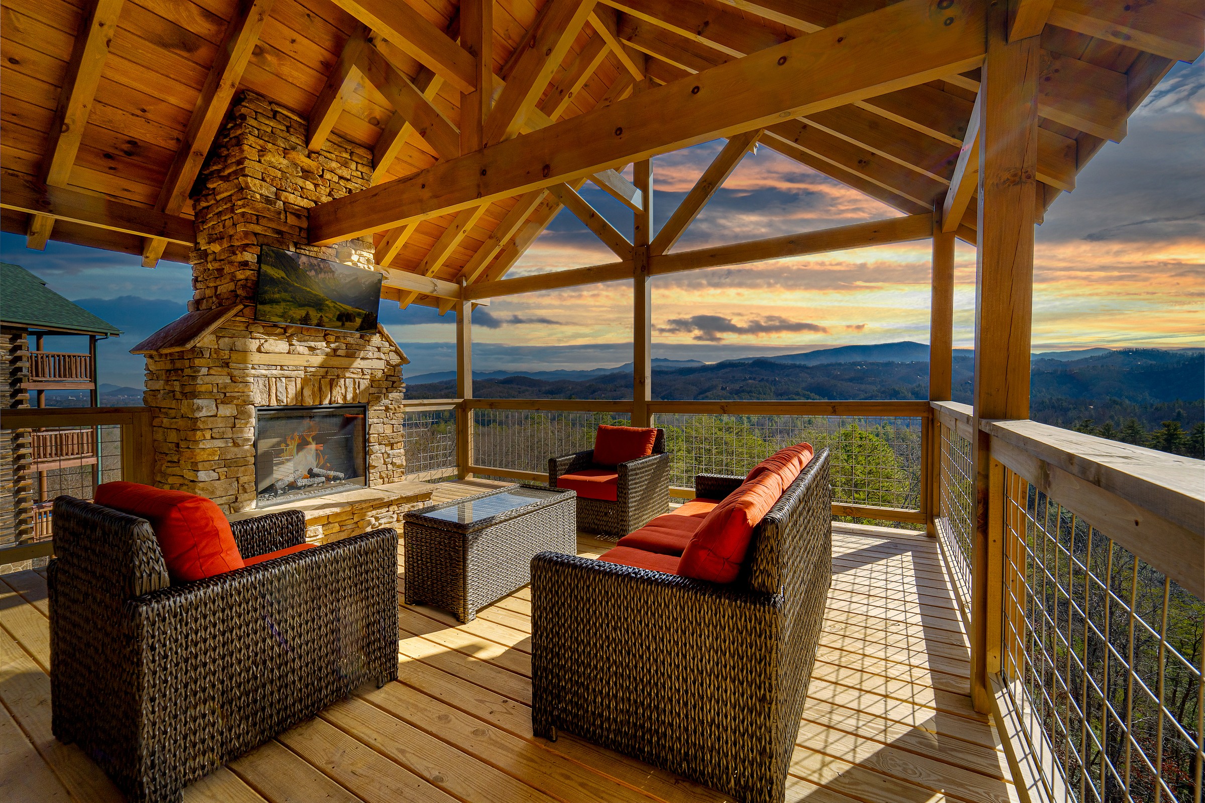 Top-level covered deck with stone fireplace and panoramic Smoky Mountain views