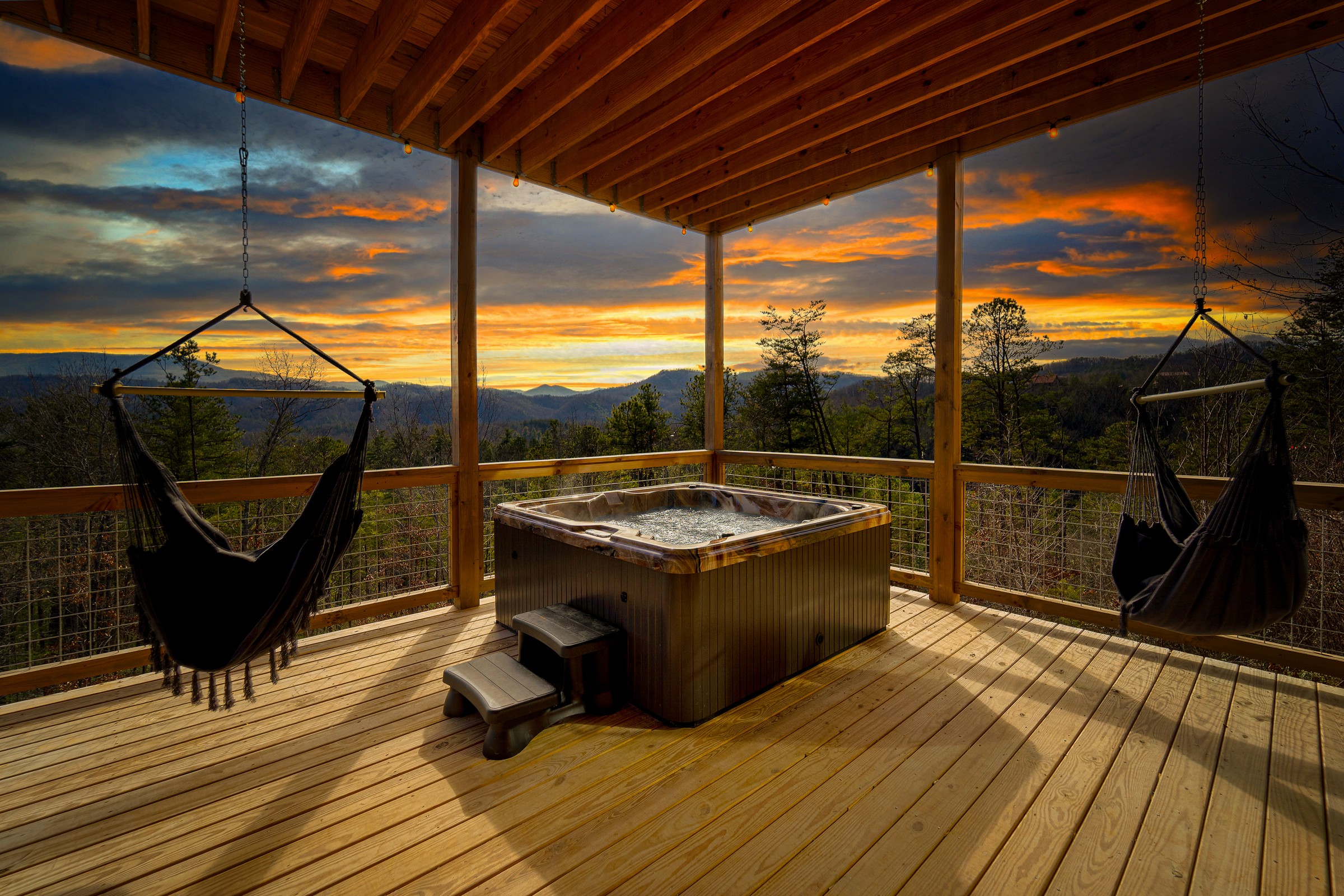 Hot tub with hanging hammock chairs and panoramic Smoky Mountain sunset