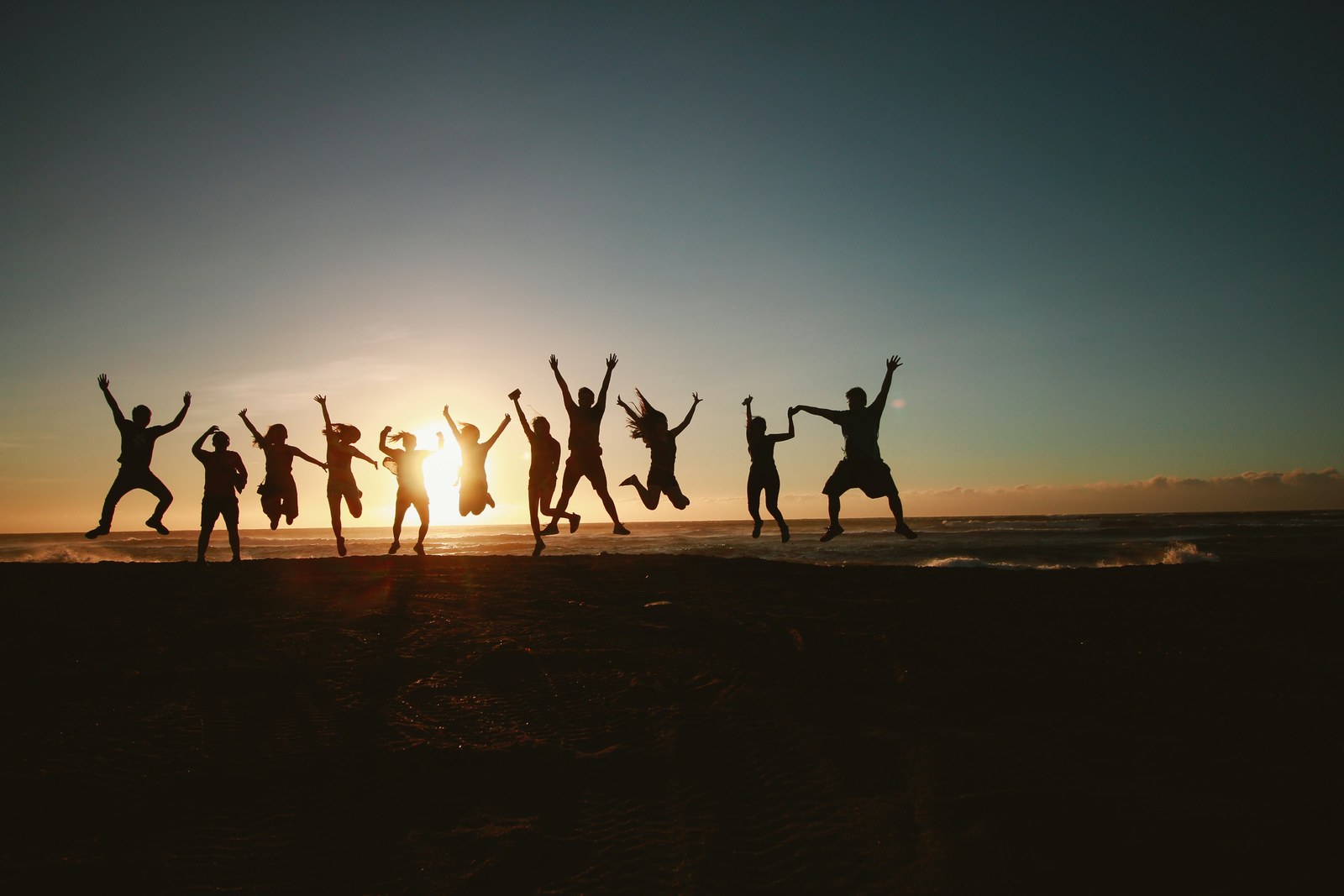 Family jumping for joy together on the beach at sunset
